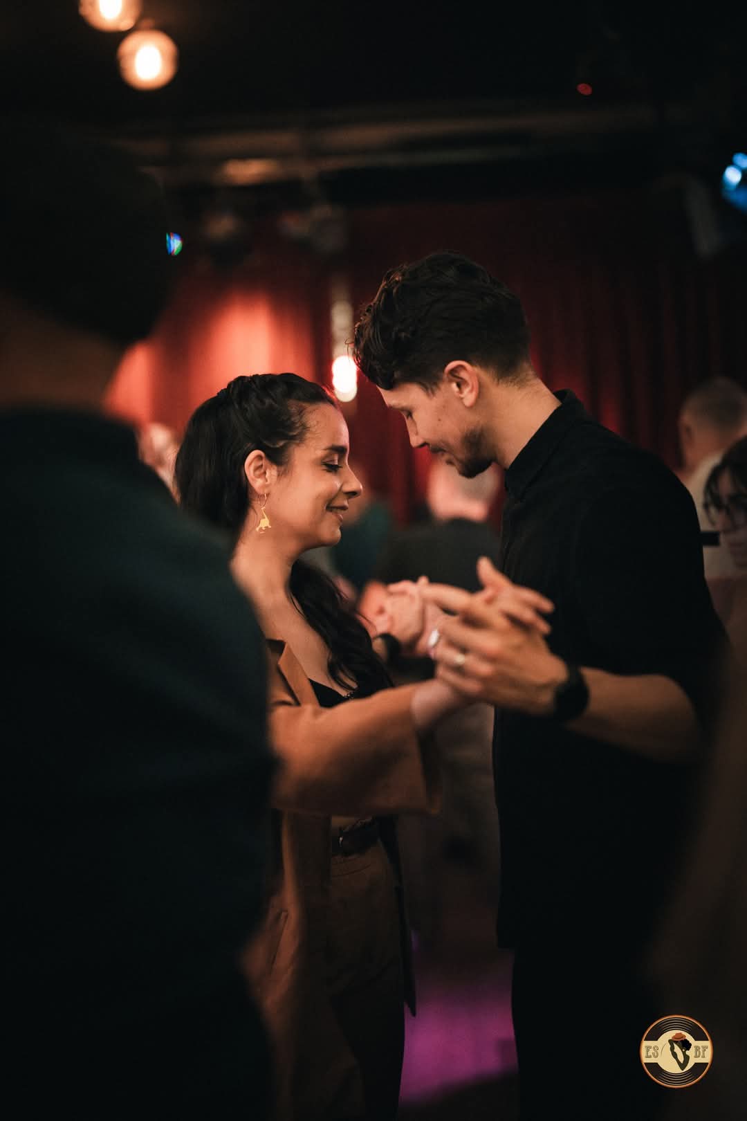 Abigail smiling through a partner dance under warm venue lights