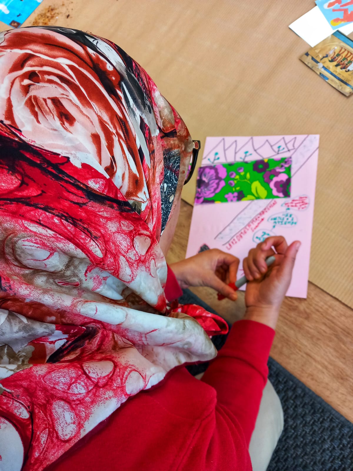 Workshop participant in a patterned headscarf working on a collage artwork, from the art therapy workshops